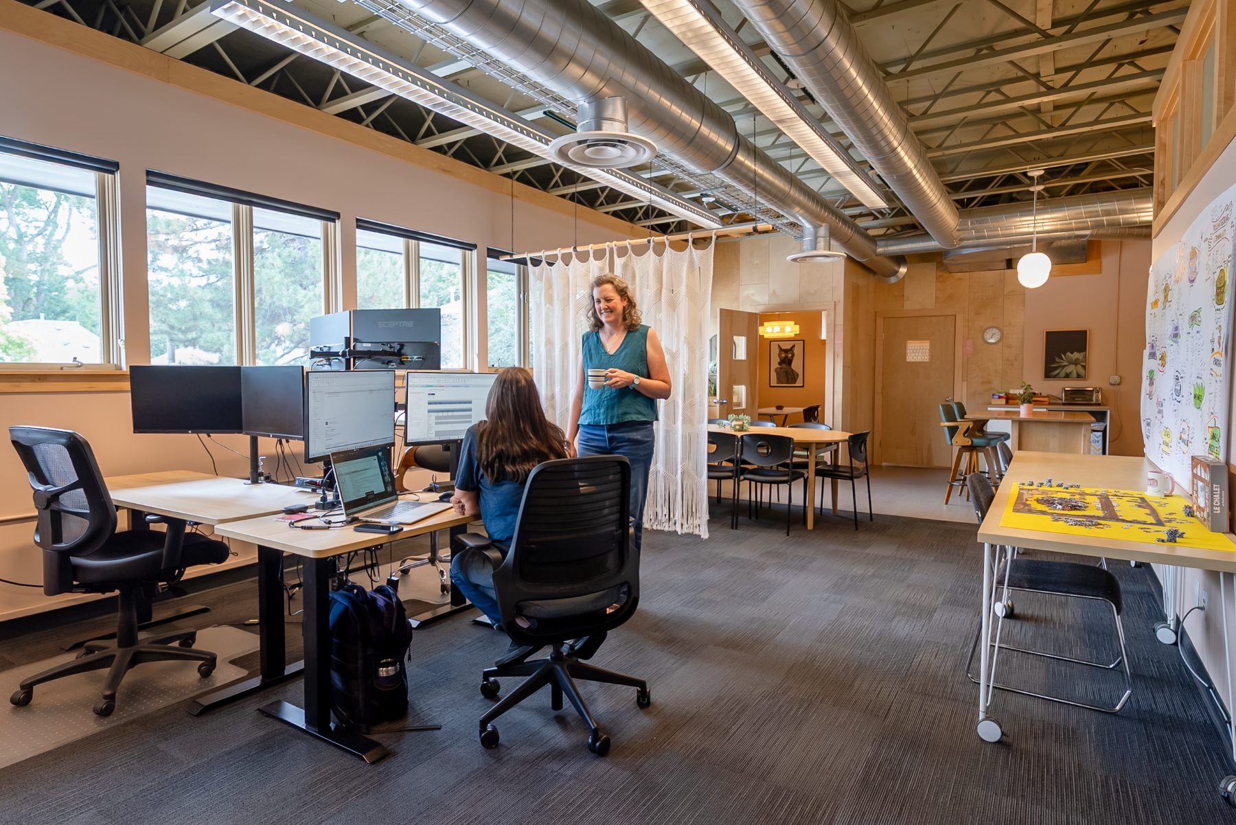 Members chatting over coffee at sit/stand desks